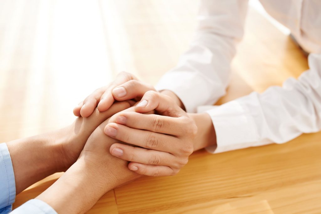 Resized for Web 175 Close up photograph of two white women holding hands across a table.