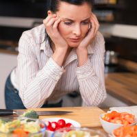 Depressed young woman in kitchen